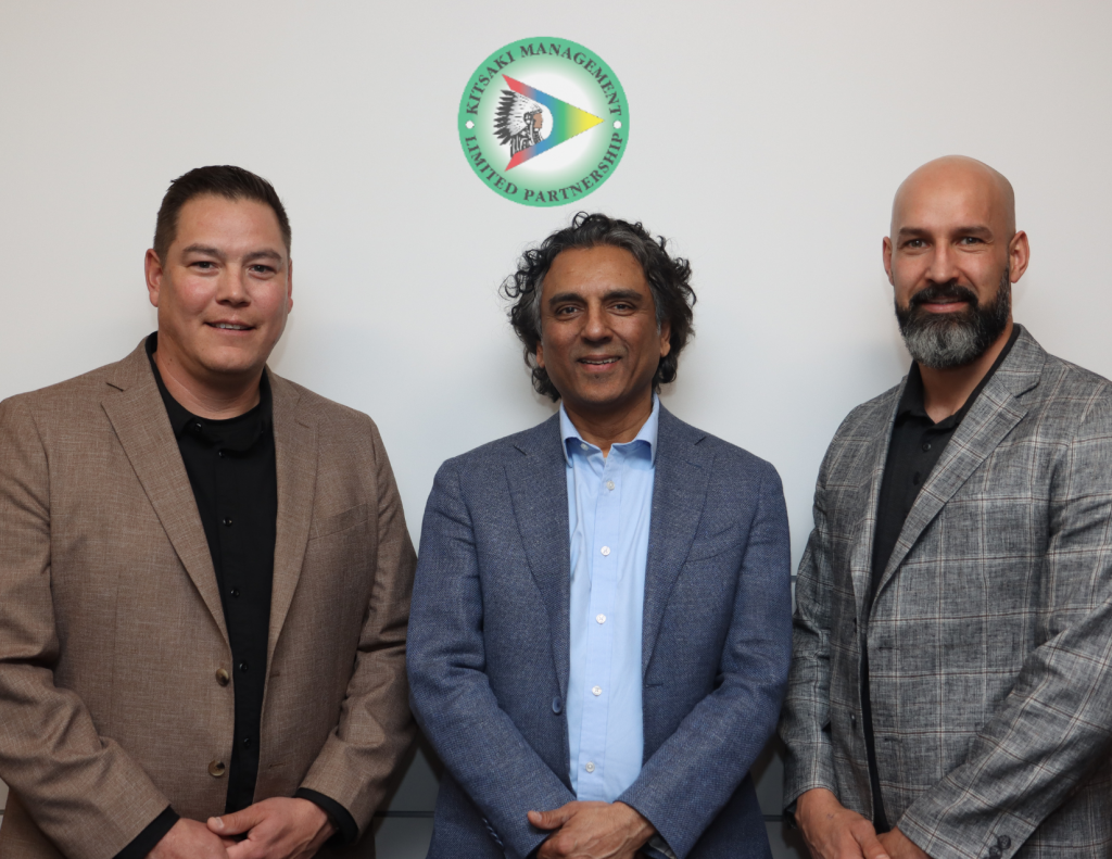 Three men standing together under a Kitsaki Management logo. Two men work at SaskPower and the other is the CEO of Kitsaki